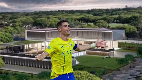 Cristiano Ronaldo celebrates an Al Nassr goal by putting his arms out wearing the jersey while a mansion is on the background.