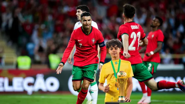Cristiano Ronaldo celebrates his goal with Diogo Jota while Cristiano Ronaldo Jr holds a trophy.
