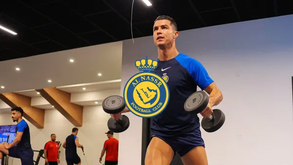 Cristiano Ronaldo is working out with dumbbells while wearing an Al Nassr training shirt and the Al Nassr logo is in the middle.