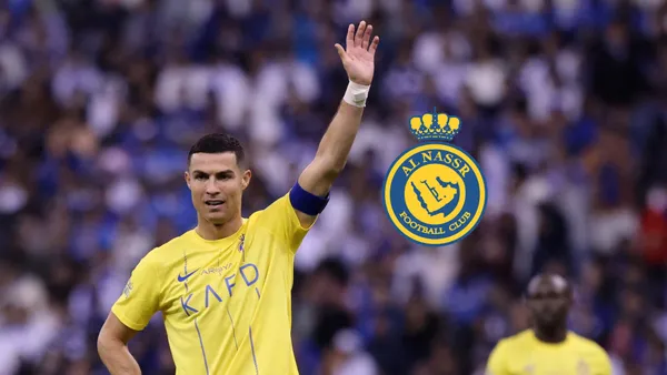Cristiano Ronaldo lifts his hand up while wearing the Al Nassr jersey and the Al Nassr badge is next to him. (Source: Al Nassr Zone X)