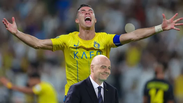 Cristiano Ronaldo screams with joy and with his arms out; the FIFA President, Gianni Infantino, smiles.