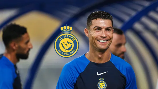 Cristiano Ronaldo smiles as he wears an Al Nass training shirt with an Al Nassr logo next to him.