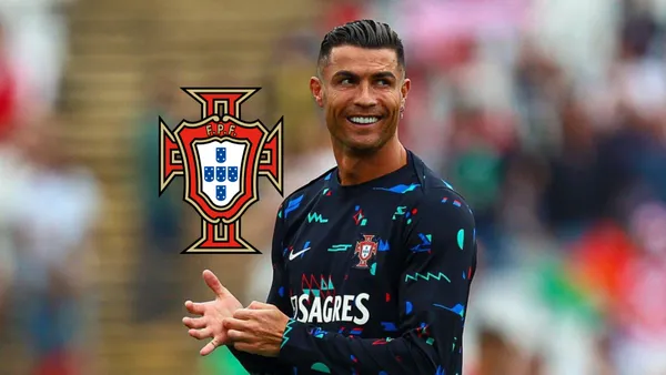 Cristiano Ronaldo smiles while wearing the training kit of Portugal and the Portugal national team badge is next to him.