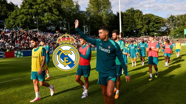 Cristiano Ronaldo waves to the fans while wearing the Portugal training kit and the Real Madrid badge is next to him.