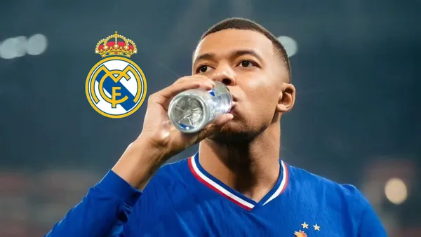 Kylian Mbappé is drinking water while wearing the France national team jersey and the Real Madrid badge is next to him.