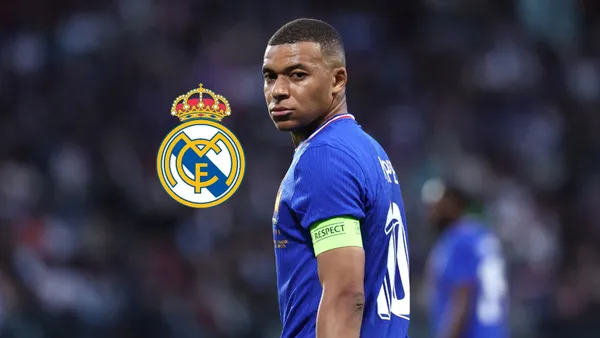 Kylian Mbappé looks back while wearing the French national team jersey and the Real Madrid badge is next to him.