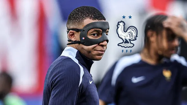 Kylian Mbappé looks to the side while he wears the black mask during training and the French national team badge is next to him. (Source: Centre Goals X)