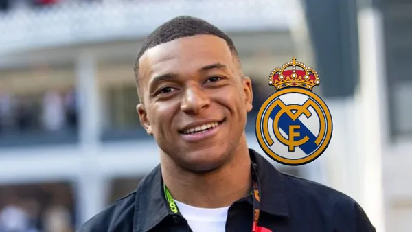 Kylian Mbappé smiles while the Real Madrid badge is next to him.