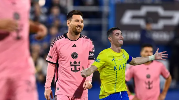 Lionel Messi slightly smiles wearing an Inter Miami kit while Cristiano Ronaldo puts his arms out with an Al Nassr kit on.