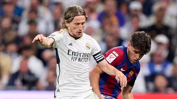 Real Madrid's Luka Modric disputing the ball against FC Barcelona's Pau Cubarsi.