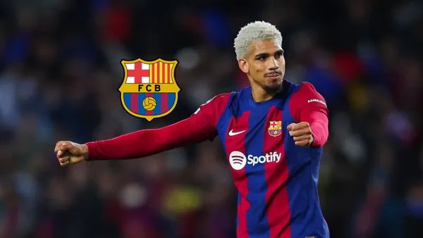 Ronald Araujo puts his arms out while wearing the FC Barcelona jersey and the FC Barcelona badge is next to him.