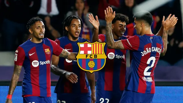 The FC Barcelona players celebrate together after a goal is scored and the FC Barcelona badge is in the middle.