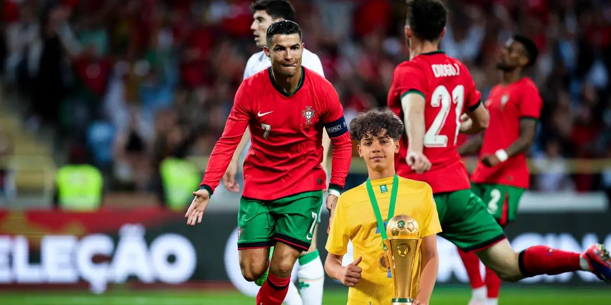 Cristiano Ronaldo celebrates his goal with Diogo Jota while Cristiano Ronaldo Jr holds a trophy.