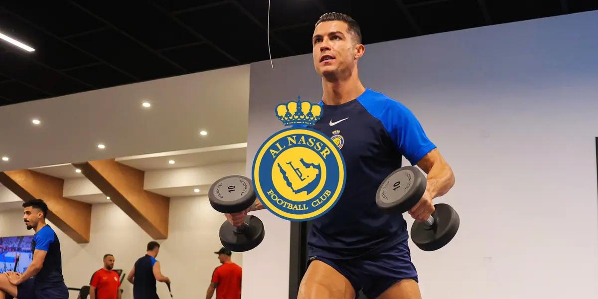 Cristiano Ronaldo is working out with dumbbells while wearing an Al Nassr training shirt and the Al Nassr logo is in the middle.