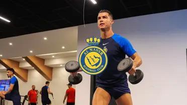 Cristiano Ronaldo is working out with dumbbells while wearing an Al Nassr training shirt and the Al Nassr logo is in the middle.
