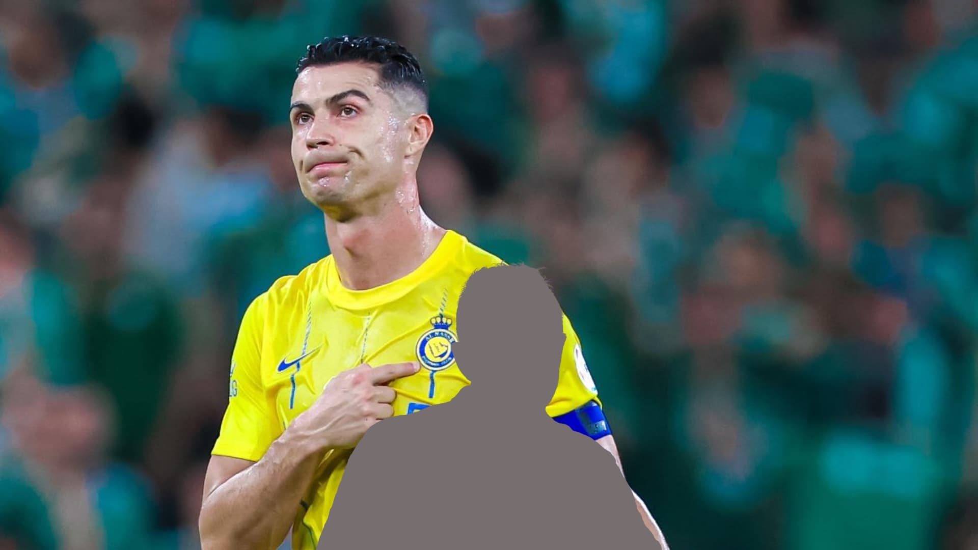 Cristiano Ronaldo points to the Al Nassr badge to the fans in the stadium.