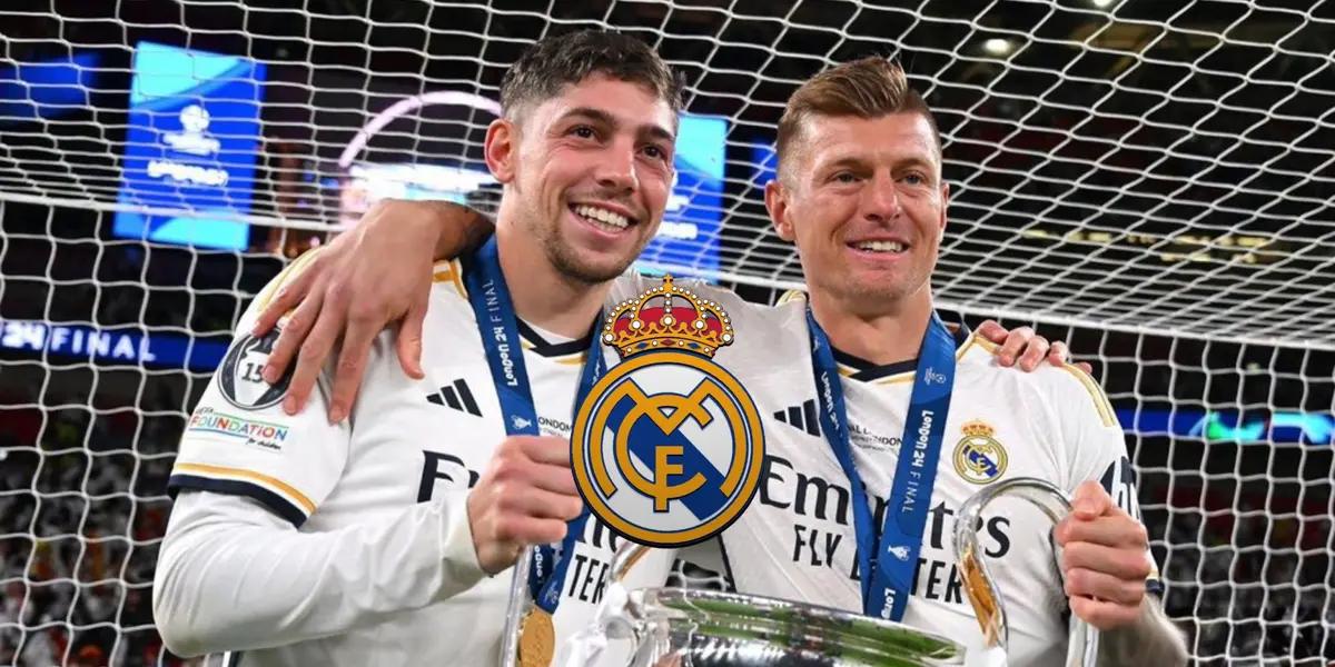 Fede Valverde and Toni Kroos smiles while holding the Champions League trophy and the Real Madrid logo is in the middle.