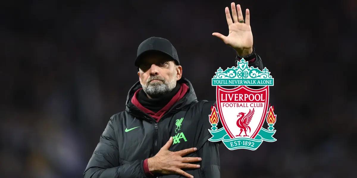 Jurgen Klopp salutes the fans in the crowd while the Liverpool badge is next to him.