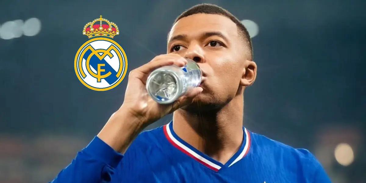 Kylian Mbappé is drinking water while wearing the France national team jersey and the Real Madrid badge is next to him.