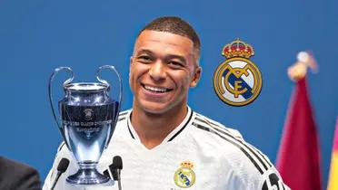 Kylian Mbappé smiles at the Real Madrid presentation while the club badge and the Champions League trophy is right next to him. (Source: UEFA, Real Madrid X)
