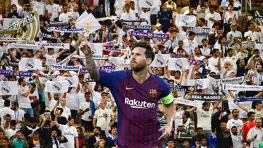 Lionel Messi points up with an FC Barcelona shirt with the background of Real Madrid fans.