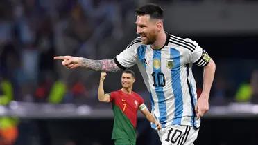 Lionel Messi smiles as he points and wears the Argentina national team jersey and Cristiano Ronaldo smiles with a fist in the air and wears the Portugal national team jersey.