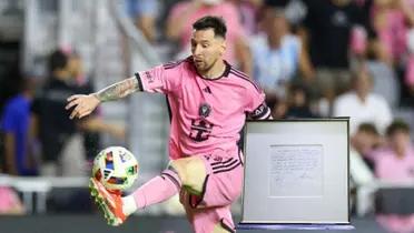 Lionel Messi touches the ball with his foot wearing an Inter Miami kit while his napkin contract is next to him.