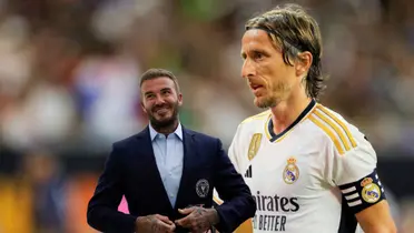 Luka Modric on the pitch wearing a Real Madrid shirt while David Beckham smiles wearing a suit with the Inter Miami logo.