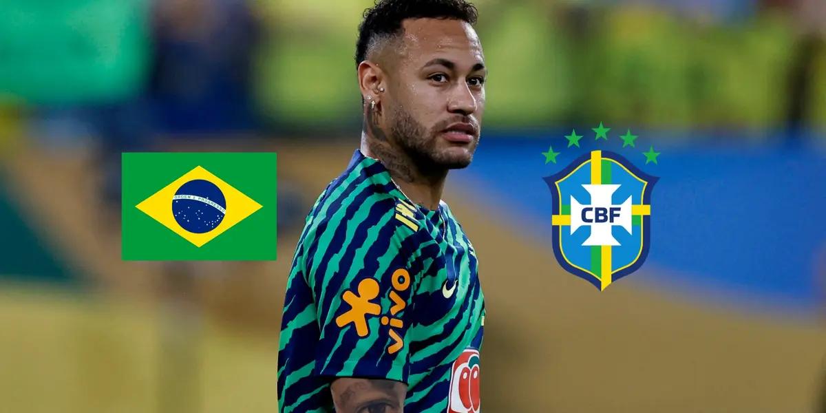 Neymar Jr. looks to the side while he is warming up; the Brazil flag and the Brazilian national team badge is next to him. (Source: REUTERS)
