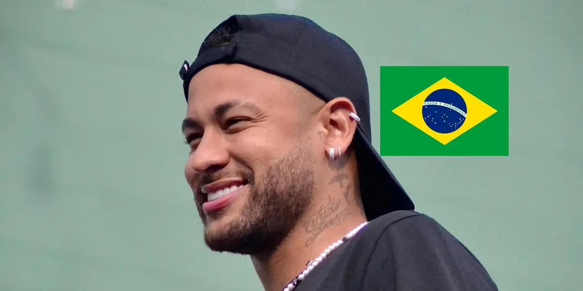 Neymar Jr. smiles while he wears a hat and the Brazil flag is next to him. (Source: Team Neymar X)