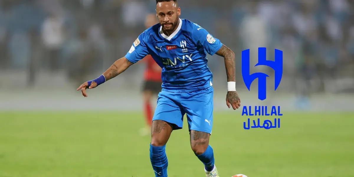 Neymar looks at the ball while wearing the Al Hilal jersey and the Al Hilal logo is next to him.