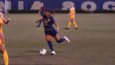 Stefany Ferrer Van Ginkel is playing football and is about to kick the ball.